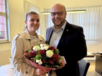 Ein lächelnder Mann und eine Frau mit einem Blumenstrauß.