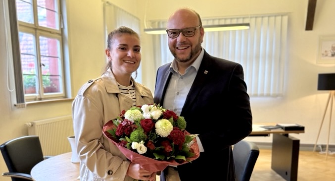 Ein lächelnder Mann und eine Frau mit einem Blumenstrauß.