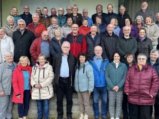 Große Seniorengruppe lächelt gemeinsam für ein Gruppenfoto im Freien.