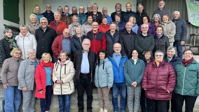 Große Seniorengruppe lächelt gemeinsam für ein Gruppenfoto im Freien.