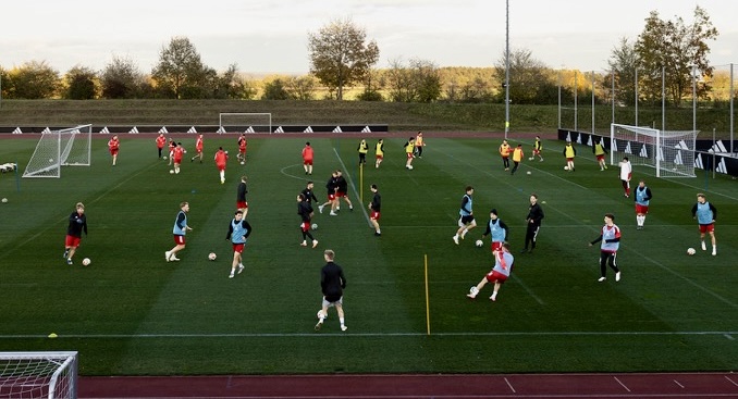 Fußballspieler trainieren auf einem grünen Rasenplatz im Freien.
