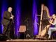 Mann spielt Klarinette und Frau spielt Harfe auf Bühne.