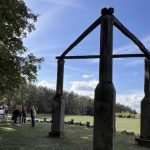 Historische Exkursion rund um Mudau Große hölzerne Tor-Skulptur auf einer Wiese mit Besuchergruppe.