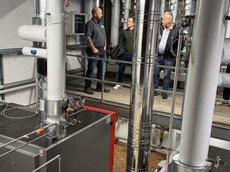Vier Männer begutachten eine industrielle Heizungsanlage.