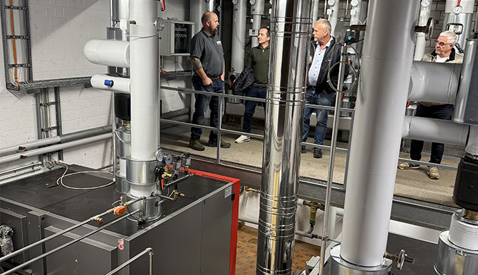 Vier Männer begutachten eine industrielle Heizungsanlage.
