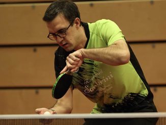 Tischtennisspieler im grünen Trikot beim Aufschlag an der Platte.