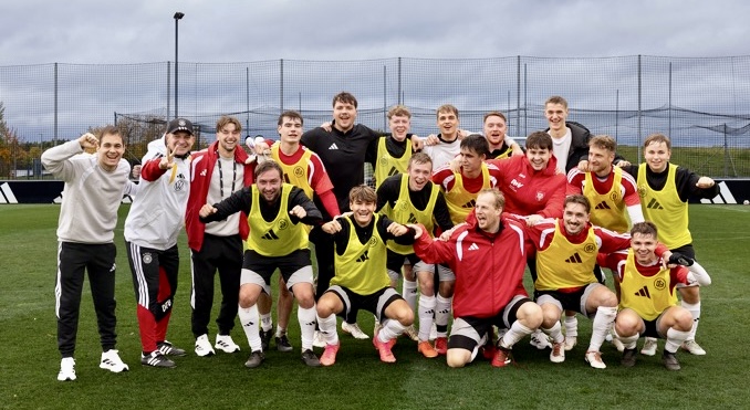 Junge Fußballspieler in Trainingskleidung posieren fröhlich für ein Gruppenfoto.