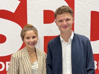 Zwei junge Personen lächelnd vor einem SPD-Hintergrund.
