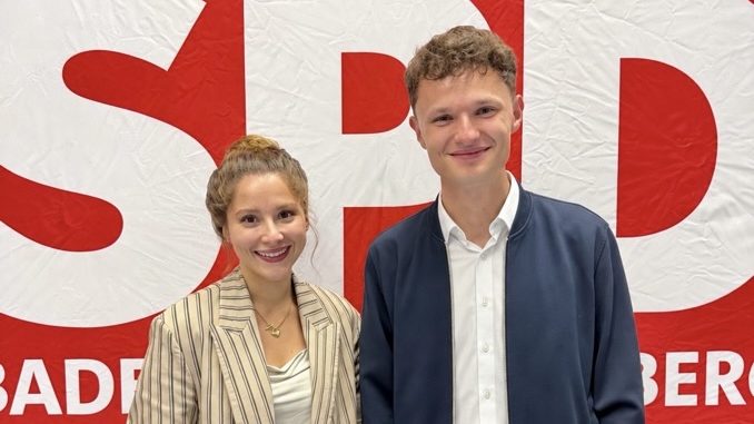 Zwei junge Personen lächelnd vor einem SPD-Hintergrund.