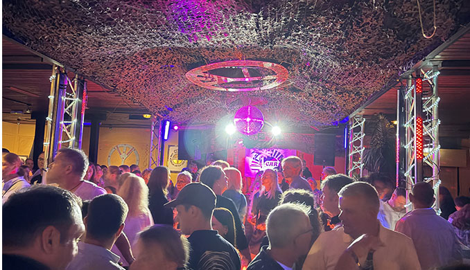 Menschenmenge feiert in einem beleuchteten Club mit Diskokugel.