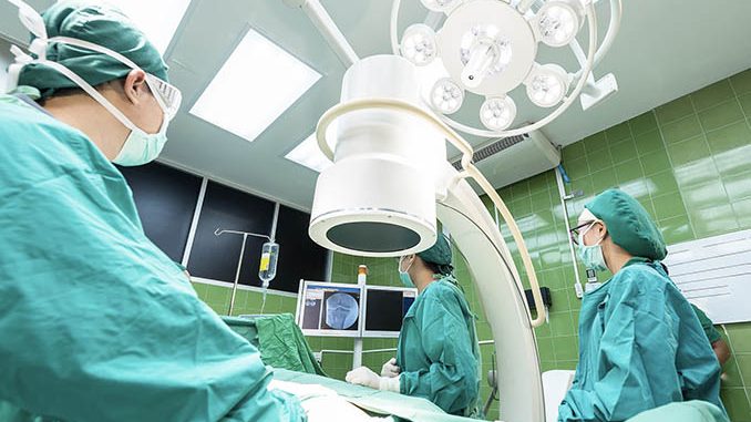 Chirurgenteam im Operationssaal mit mobilem C-Bogen Röntgengerät