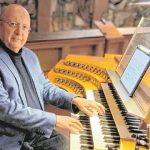 Ein Mann an einer Kirchenorgel mit digitalem Notenblatt.