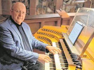 Ein Mann an einer Kirchenorgel mit digitalem Notenblatt.