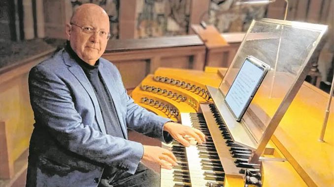 Ein Mann an einer Kirchenorgel mit digitalem Notenblatt.