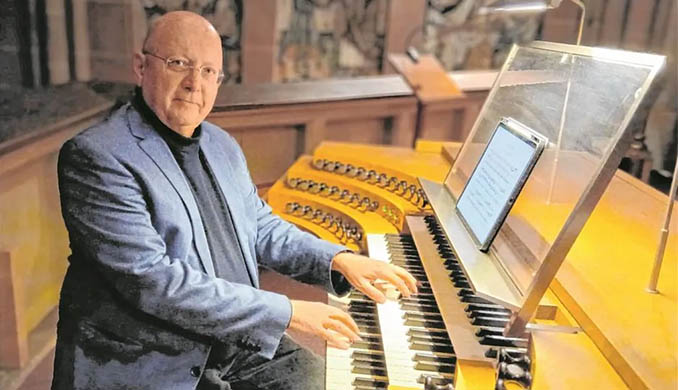 Ein Mann an einer Kirchenorgel mit digitalem Notenblatt.